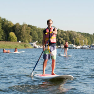 Ein Junge der auf dem See SUP fährt.
