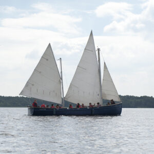 Eine Gruppe von Menschen segelt auf einem Segelboot über den See.