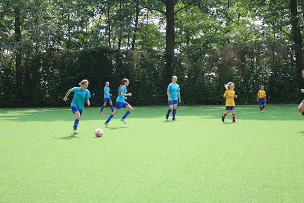 Kinder spielen Fußball auf einem Sportplatz.