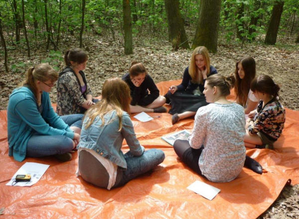 Gruppe von Jugendlichen sitzen auf einer Plane im Wald.