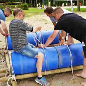 Eine Gruppe baut ein ein Floß am Strand.