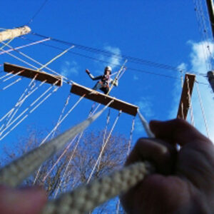 Person klettert im Hochseilgarten.