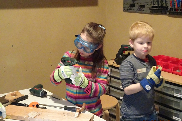 Zwei Kinder, die in der Forscherwelt mit einer Heißkleberpistole experimentieren.