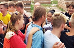 Eine Gruppe steht eng beieinander und legt die Arme umeinander.