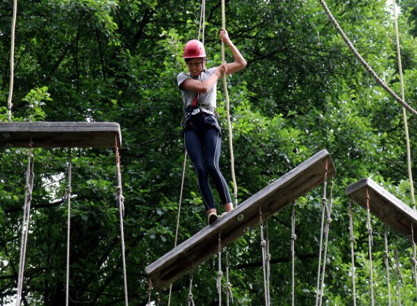 Eine Person klettert im Hochseilgarten.