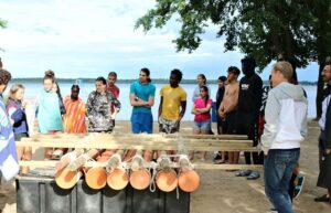 Eine Gruppe steht am Strand um ein selbstgebautes Floß.