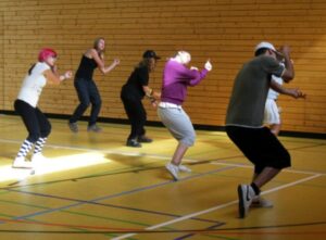 Jugendliche tanzen in der Sporthalle.