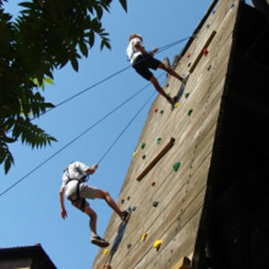 Zwei Jugendliche, die an der Outdoor-Kletterwand hochklettern.