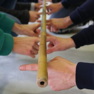 Mehrere Personen halten gemeinsam einen langen Holzstab.