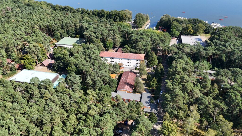 Vogelperspektive vom Jugendbildungszentrum mit einzelnen Gebäuden, einem Hafen und von Bäumen umgeben.