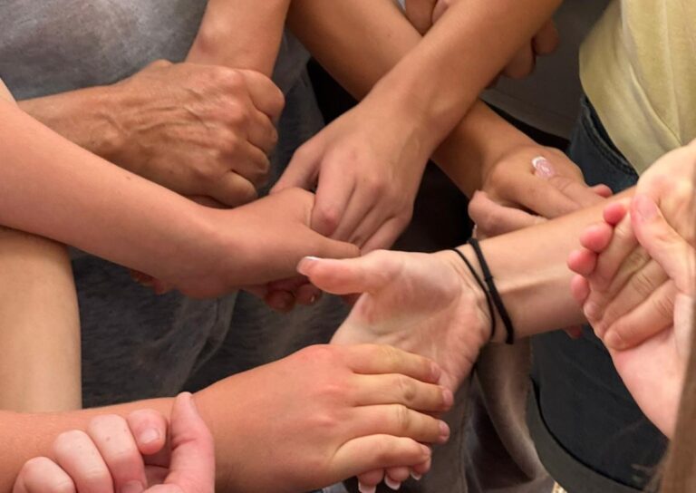 Mehrere Hände greifen ineinander in einer Geste des Zusammenhalts.