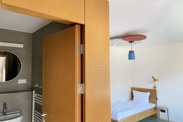 Zimmer auf dem Weißen Berg mit Bett und Eingang zum Badezimmer.