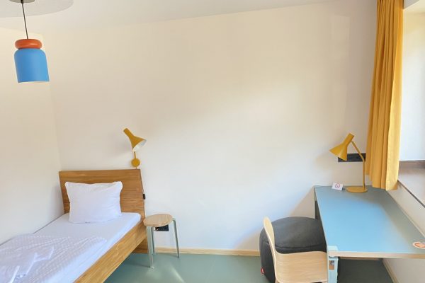 Zimmer auf dem Weißen Berg mit Bett und Schreibtisch.